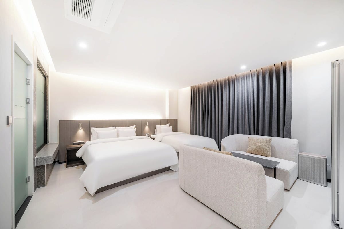 Ein modernes Hotelzimmer mit zwei Betten, einer Sitzecke, einem kleinen Tisch und einer Heizung.