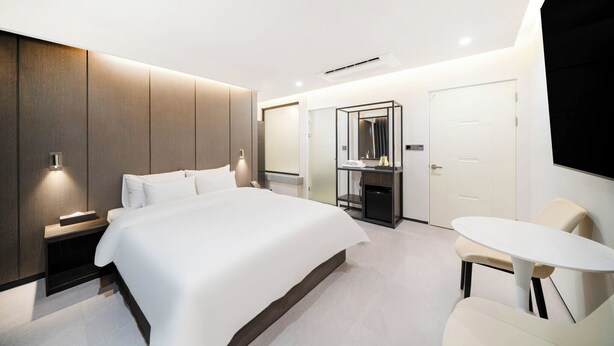 Une chambre d’hôtel moderne, dotée d’un grand lit, de tables de chevet, d’un bureau et d’une chaise.