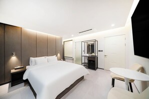 Ein modernes Hotelzimmer mit einem großen Bett, Nachttischen, einem Schreibtisch und einem Sessel.