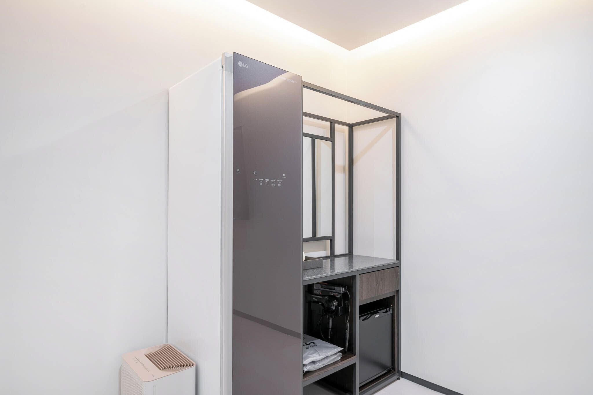 A compact, modern room with a built-in wardrobe, a small seating area, and a compact heater.