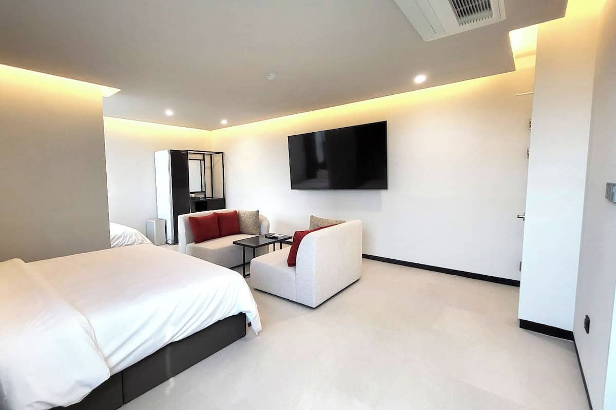 Ein modernes Hotelzimmer mit einem großen Bett, einer Couch, einem an der Wand befestigten Fernseher und einem kleinen Tisch.
