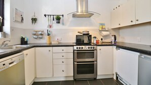 Una cocina moderna con armarios blancos, una campana extractora de acero inoxidable, un microondas y un lavavajillas.