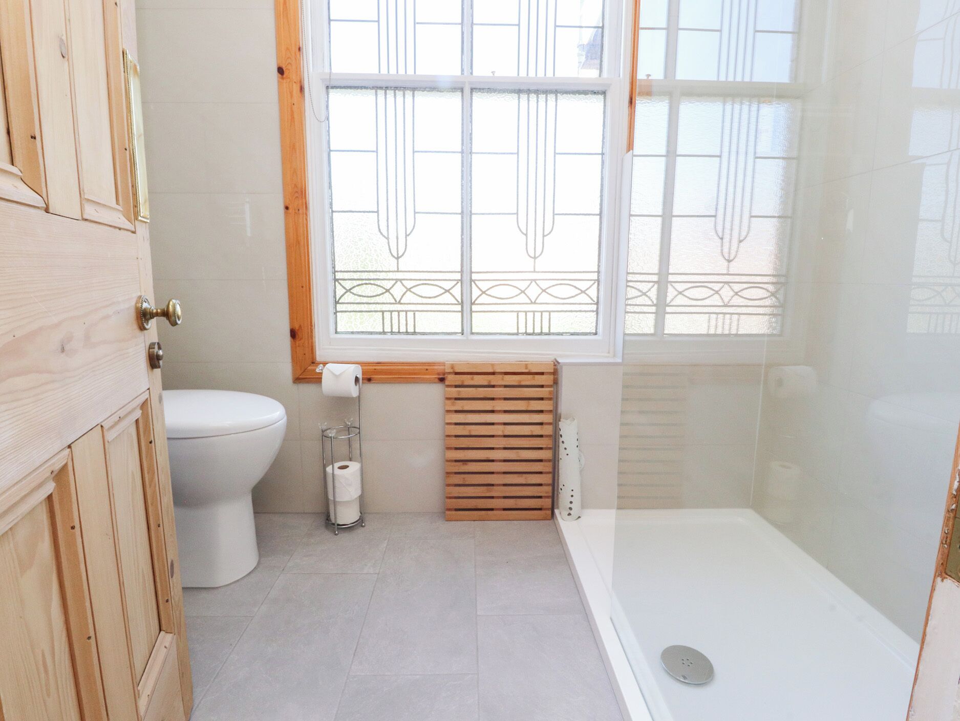 Een moderne badkamer met toilet, douche en raam met decoratieve tralies.