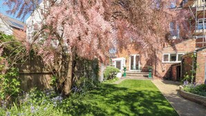 Un jardí ben cuidat amb gespa, plantes florentes i una paret de maó.