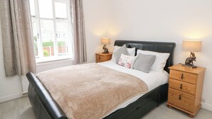 A bedroom with a bed, two bedside tables, a window with curtains, and a view of the outside. - Cherry Tree Cottage (Bakewell)