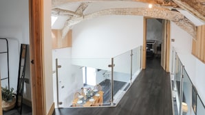 A modern interior with exposed wooden beams, a staircase, and a dining area with a table set for four. - Gwel Y Fenai (Caernarfon)