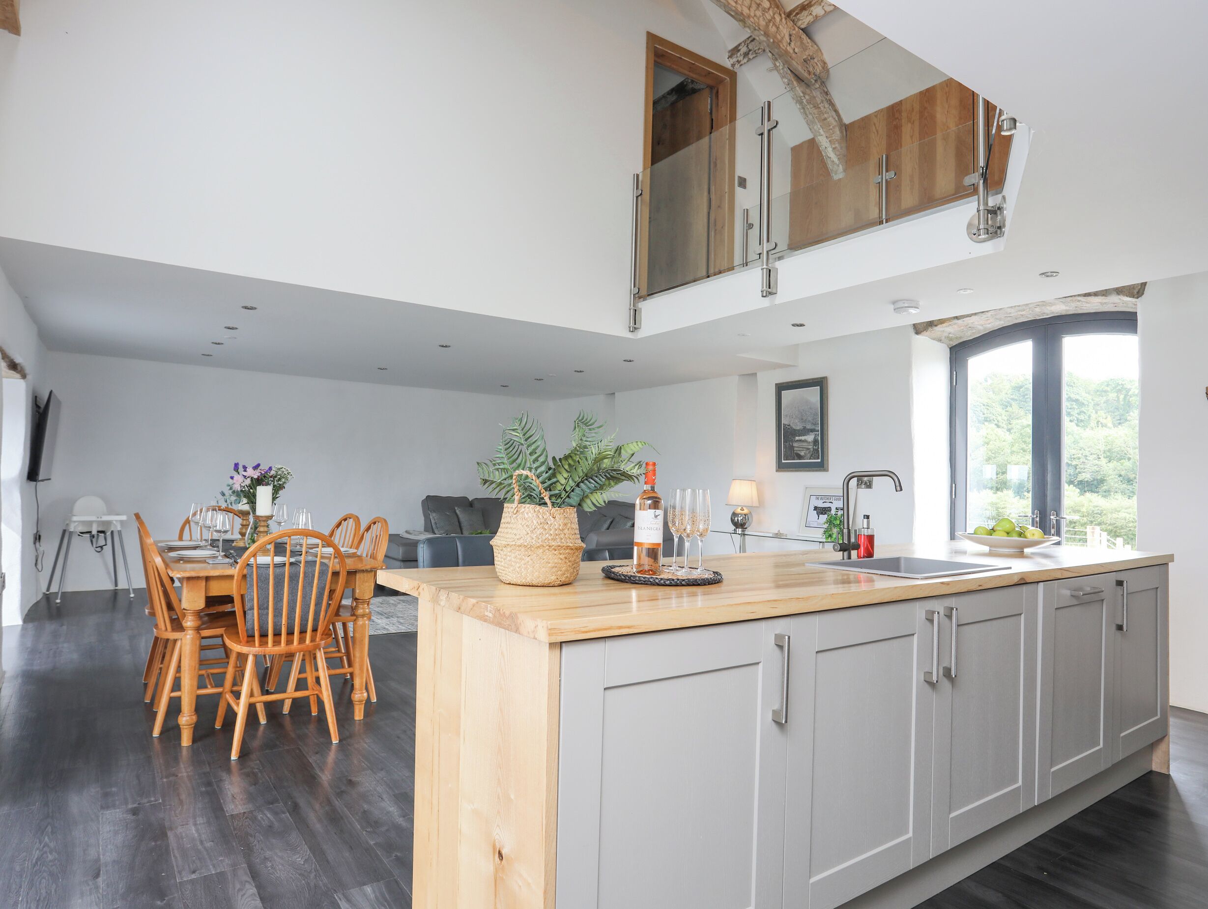 A modern kitchen with a large island, grey cabinets, and a dining area with wooden chairs.