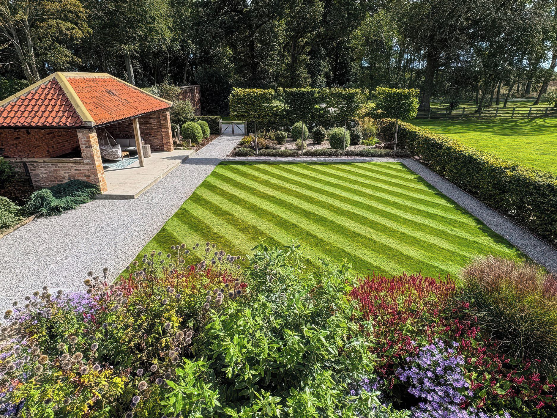 Un jardín bien cuidado con césped, una estructura de ladrillo y diversas plantas.