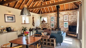 Una sala de estar acogedora con chimenea, vigas de madera y pared de piedra.