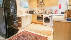 Een moderne keuken met roestvrijstalen apparatuur, houten kastjes en een vloerkleed met patroon.