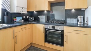 Una cucina moderna con mobili in legno, forno integrato, piano cottura a gas e macchina per il caffè.