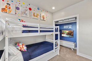 A bunk bed room with a gaming zone and artwork on the wall.