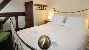 Een slaapkamer met een bed, een houten deur, een kapstok aan de muur en een hanglamp.