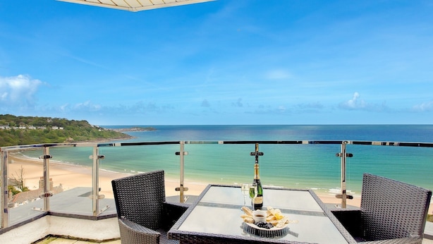 Ein Balkon mit Tisch für zwei Personen, mit Blick auf Strand und Meer.