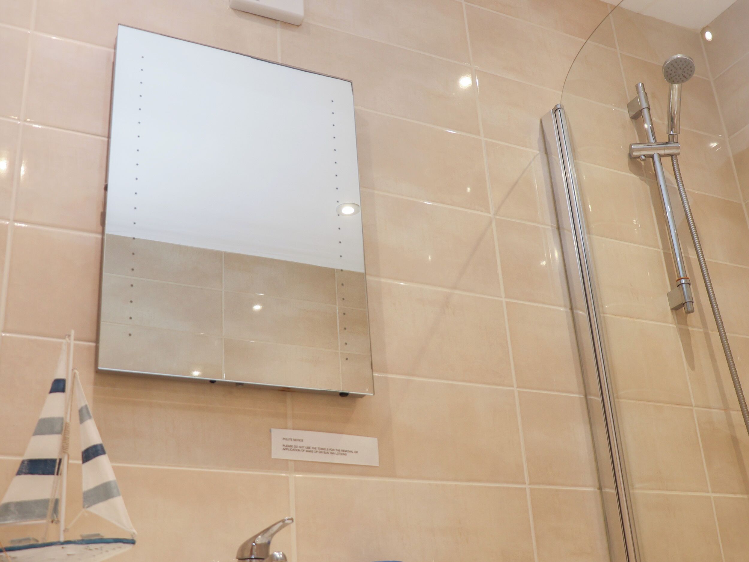 Ein Badezimmer mit Spiegel, Dusche und Handtuchhalter.