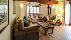 A cozy living room with a wooden ceiling, a sofa set, a coffee table, and a lamp. - Woodpit Cottage (Nottingham)