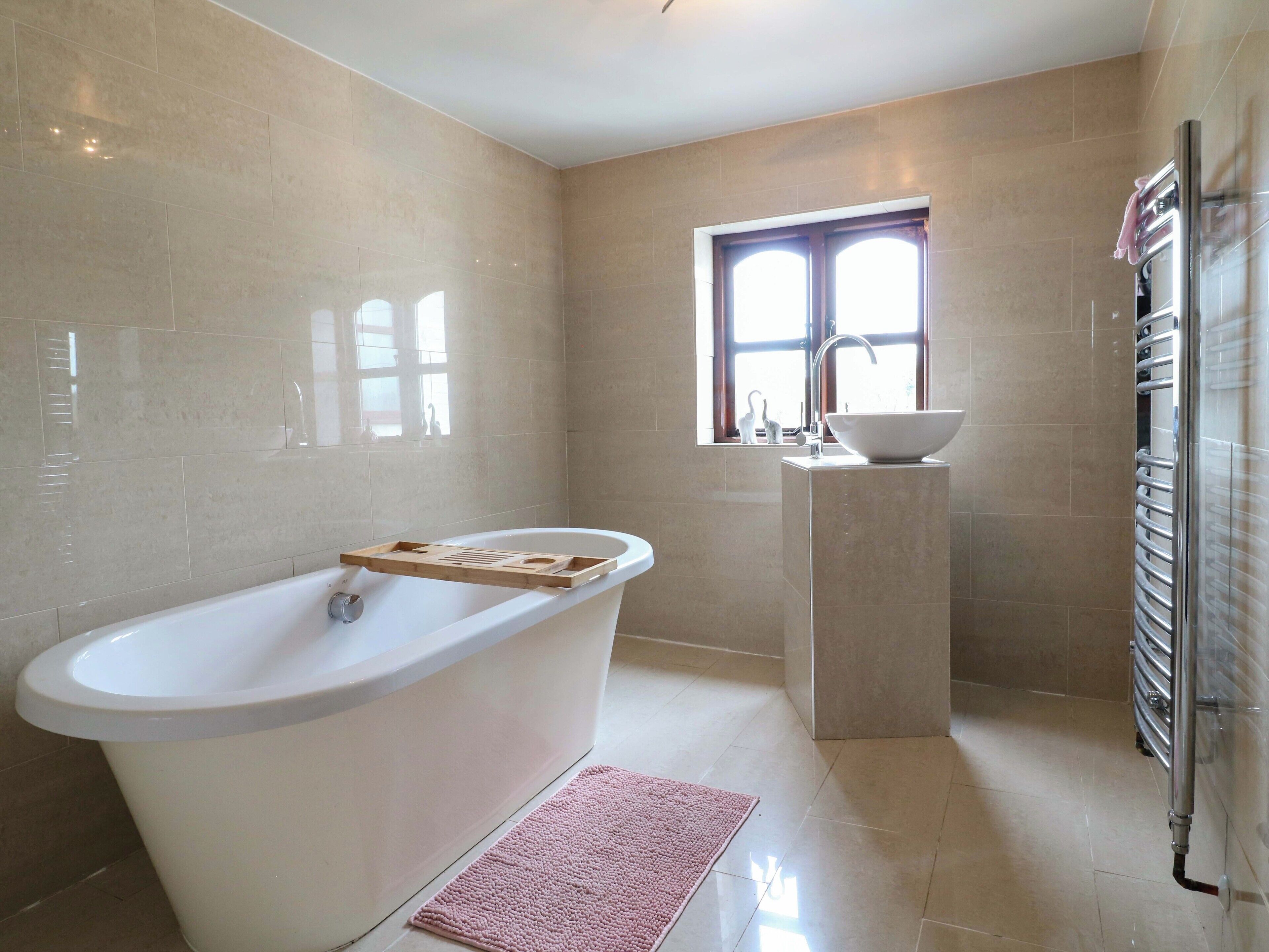 Ein Badezimmer mit einer freistehenden Badewanne, einem Fenster mit Blick und einem Waschbecken sowie einem Handtuchhalter.