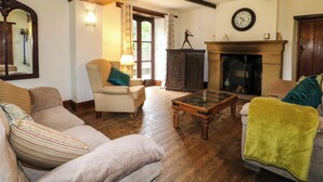 A cozy living room with a fireplace, a clock on the wall, and a large mirror. - Woodpit Cottage (Nottingham)