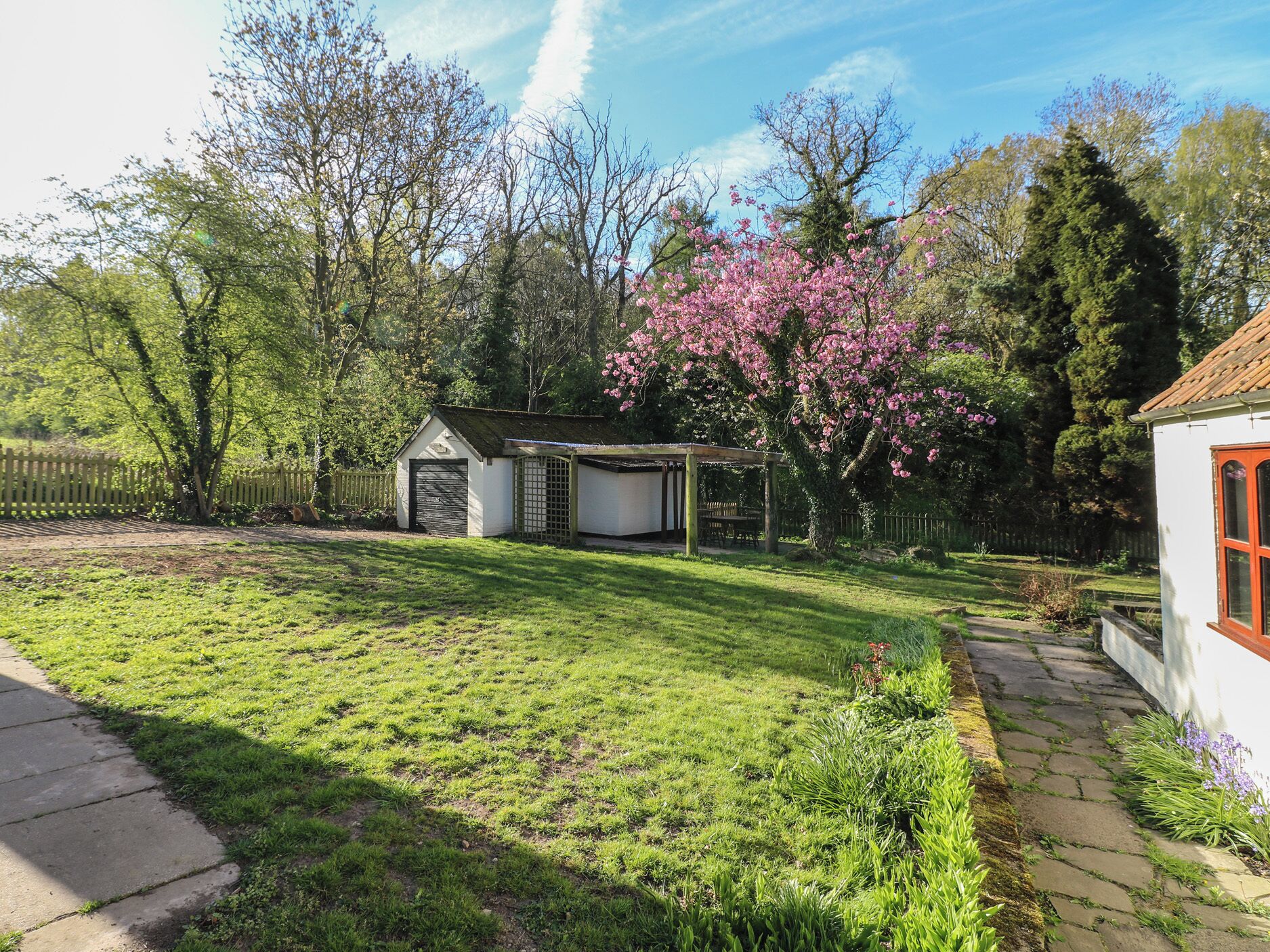 A well-maintained garden with a small shed, a gazebo, and a variety of flowering plants.