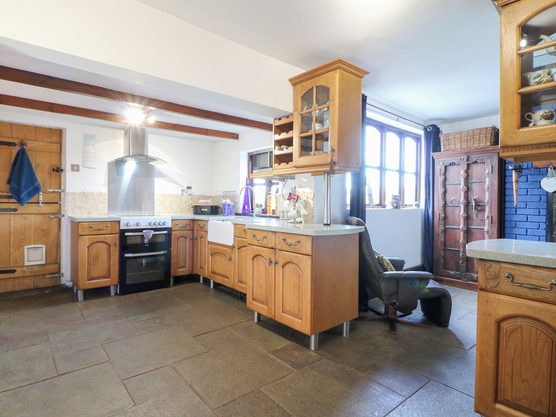 A kitchen with wooden cabinets, a built-in oven, a microwave, and a large window.