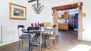 A dining area with a round table, zebra-striped chairs, a chandelier, and a framed picture on the wall. - Woodpit Cottage (Nottingham)