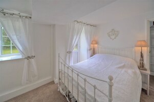 A bedroom with a white bed, white curtains, and a white radiator.