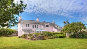 A pink house with a large lawn and a conservatory. - Ty Ffynnon (Pwllheli)