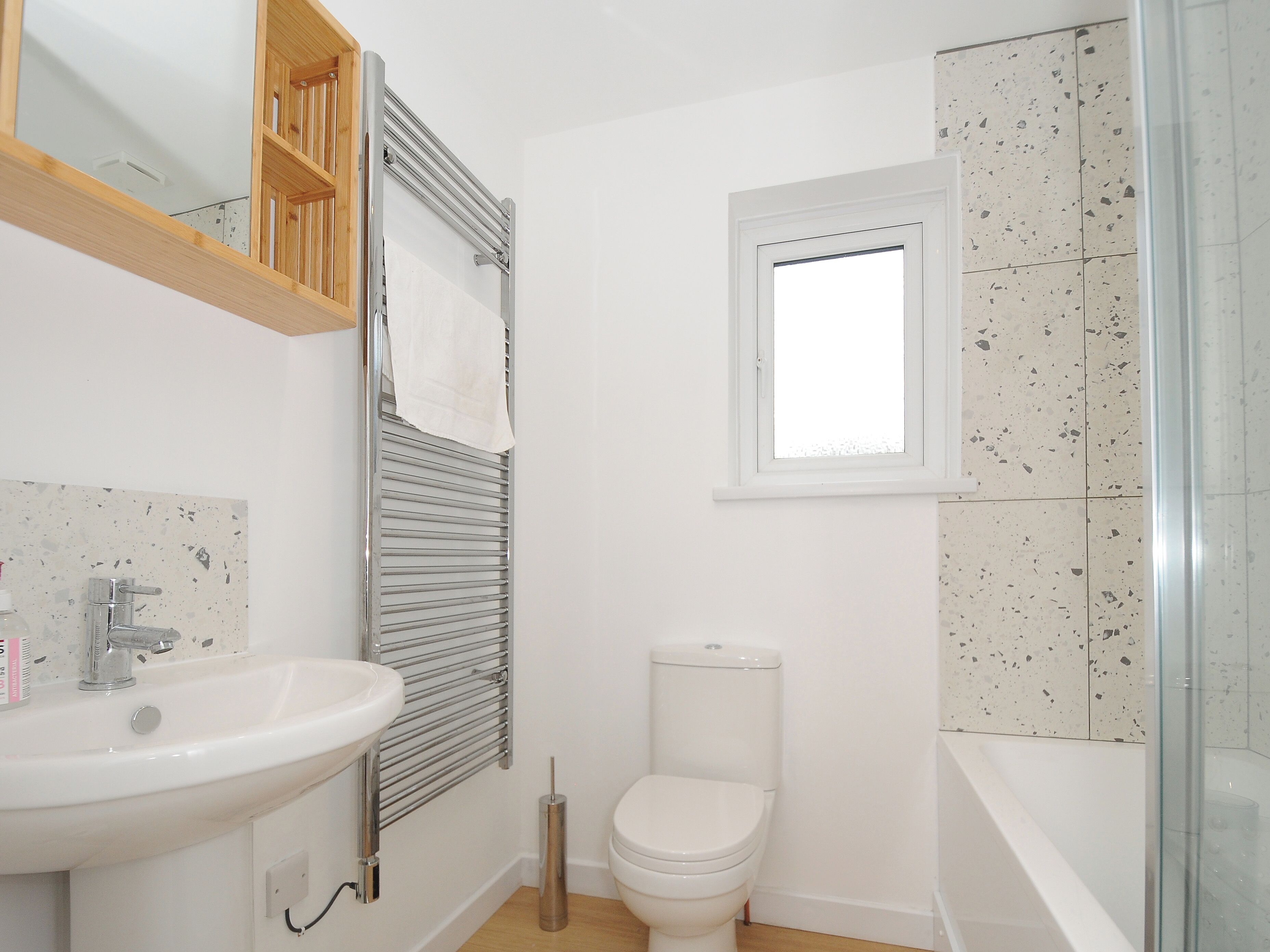 A bathroom with a white sink, toilet, and a glass shower enclosure.