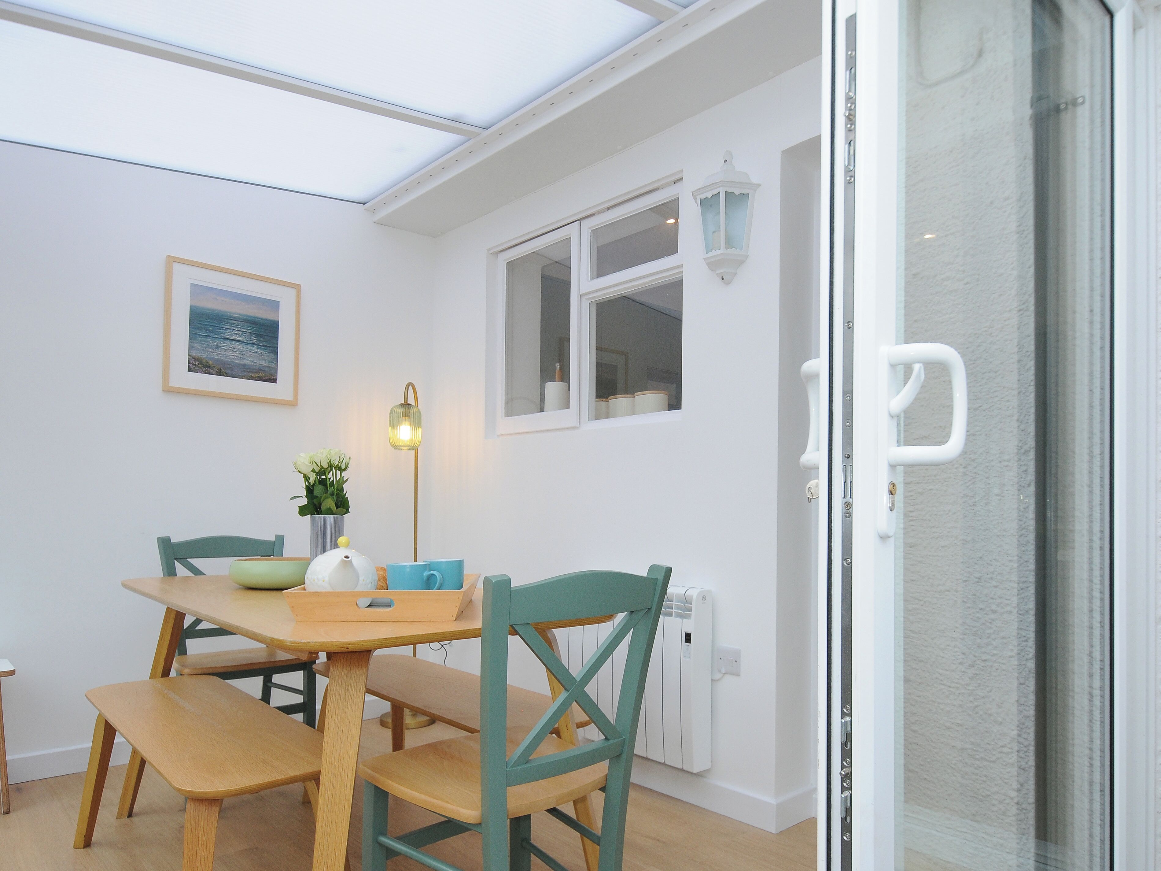 Un comedor con una mesa, sillas, una lámpara y una ventana.