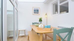 Un coin repas comprenant une table en bois, des chaises, un banc, une lampe sur pied et un tableau encadré accroché au mur.
