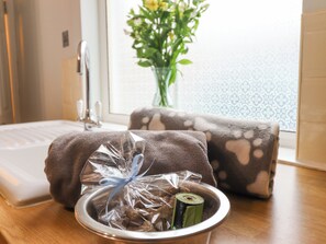 Ein Badezimmer mit Waschbecken, Handtuch, einer Geschenkverpackung und einem Blumenstrauß.