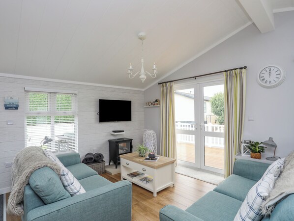 A modern living room with a television, sofa, and a fireplace. - The Warren K20 (Pwllheli)