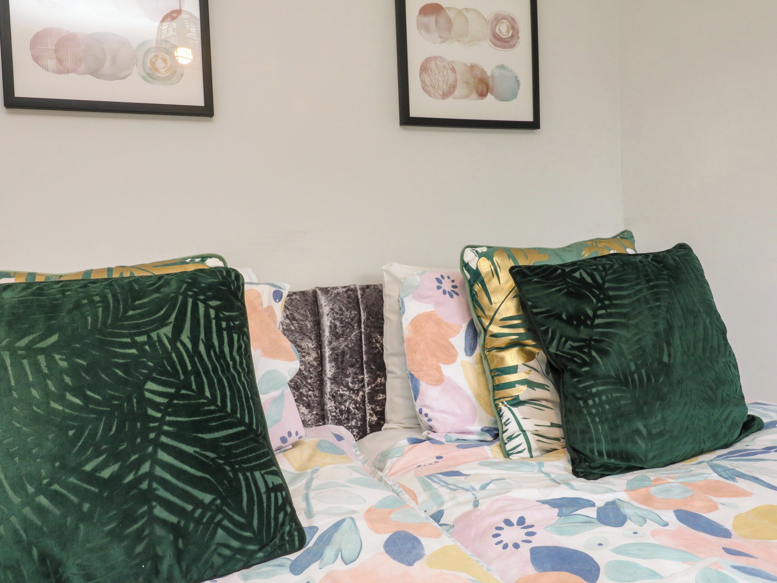 A bed with multiple pillows and a floral-patterned bedspread.