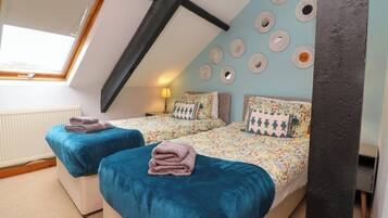 A cozy attic bedroom with two beds, a skylight, and a decorative wall with circular mirrors.