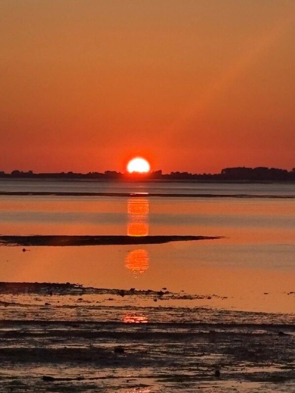 A sunset over a calm body of water with a clear reflection of the sun.