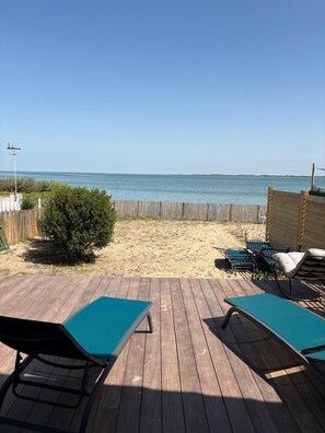 A wooden deck with lounge chairs and a view of the beach and ocean.