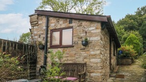 A stone cottage with a wooden bench, a potted plant, and a small table. - The Bothy (Bolton)