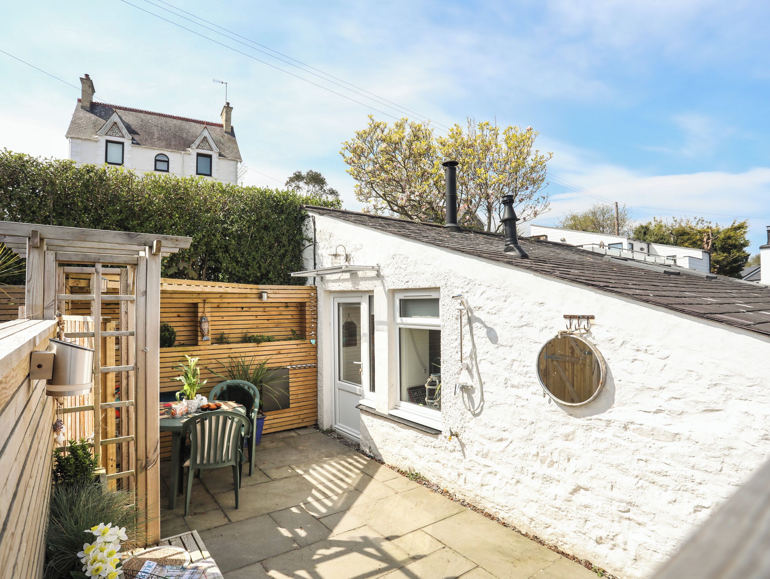 A white house with a wooden deck, a wooden fence, and a garden.