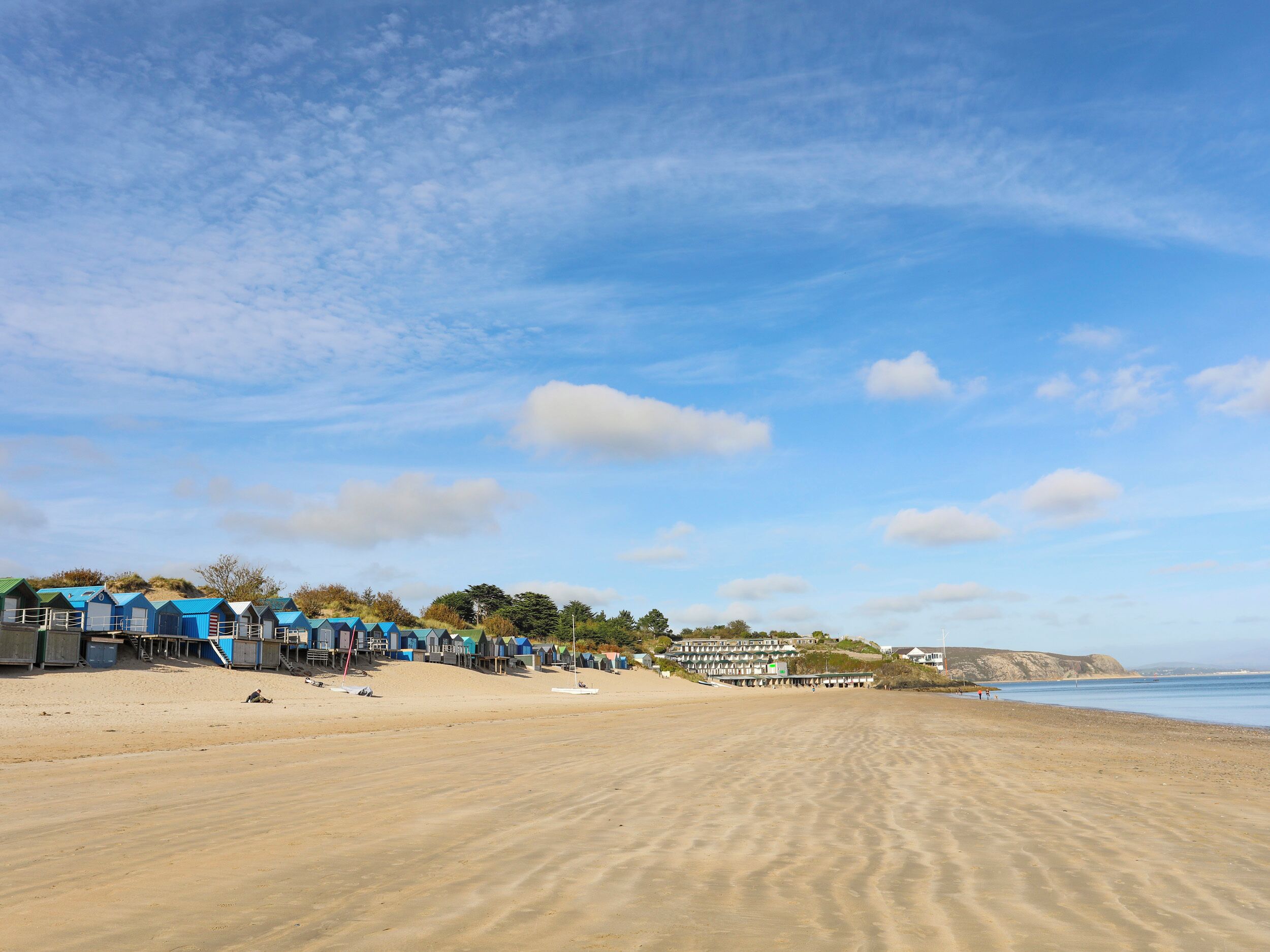 A beach with rows of beach huts and a sandy shoreline.