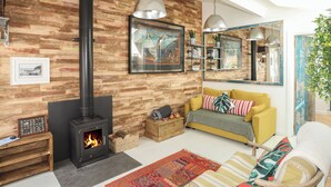 A cozy living room with a wood-paneled wall, a fireplace, a yellow sofa, and a large mirror.