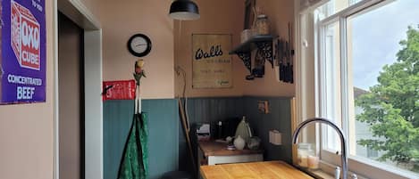 A kitchen with a wooden countertop, a sink, a clock, and various kitchen utensils.