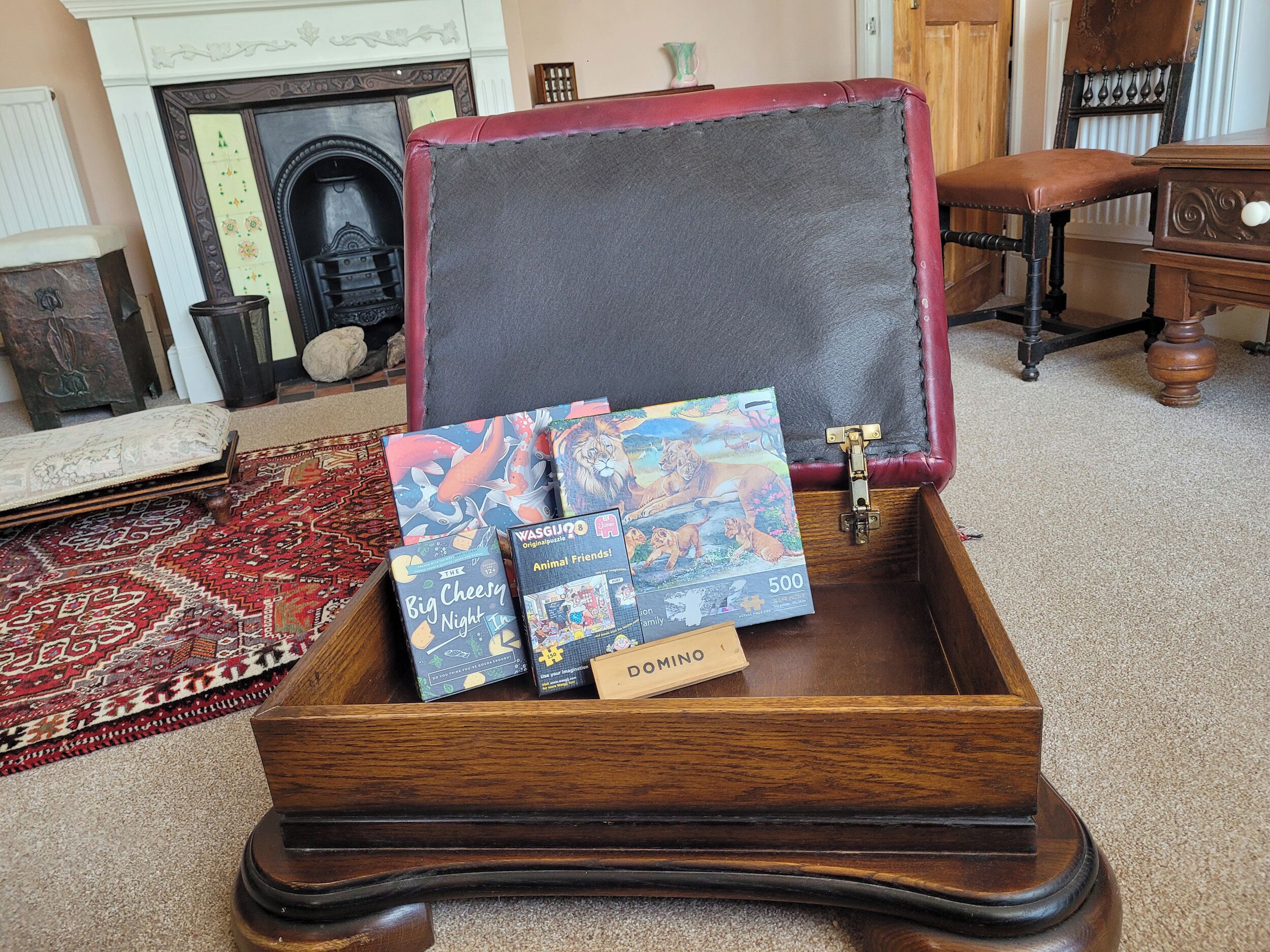 Un cofre de madera con tapa abatible, que contiene varios libros y una pequeña caja con la etiqueta 'DOMINO'.