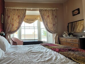 A bedroom with a bed, a dresser, a chair, and a window with curtains. - Nelson's View (Ryde)