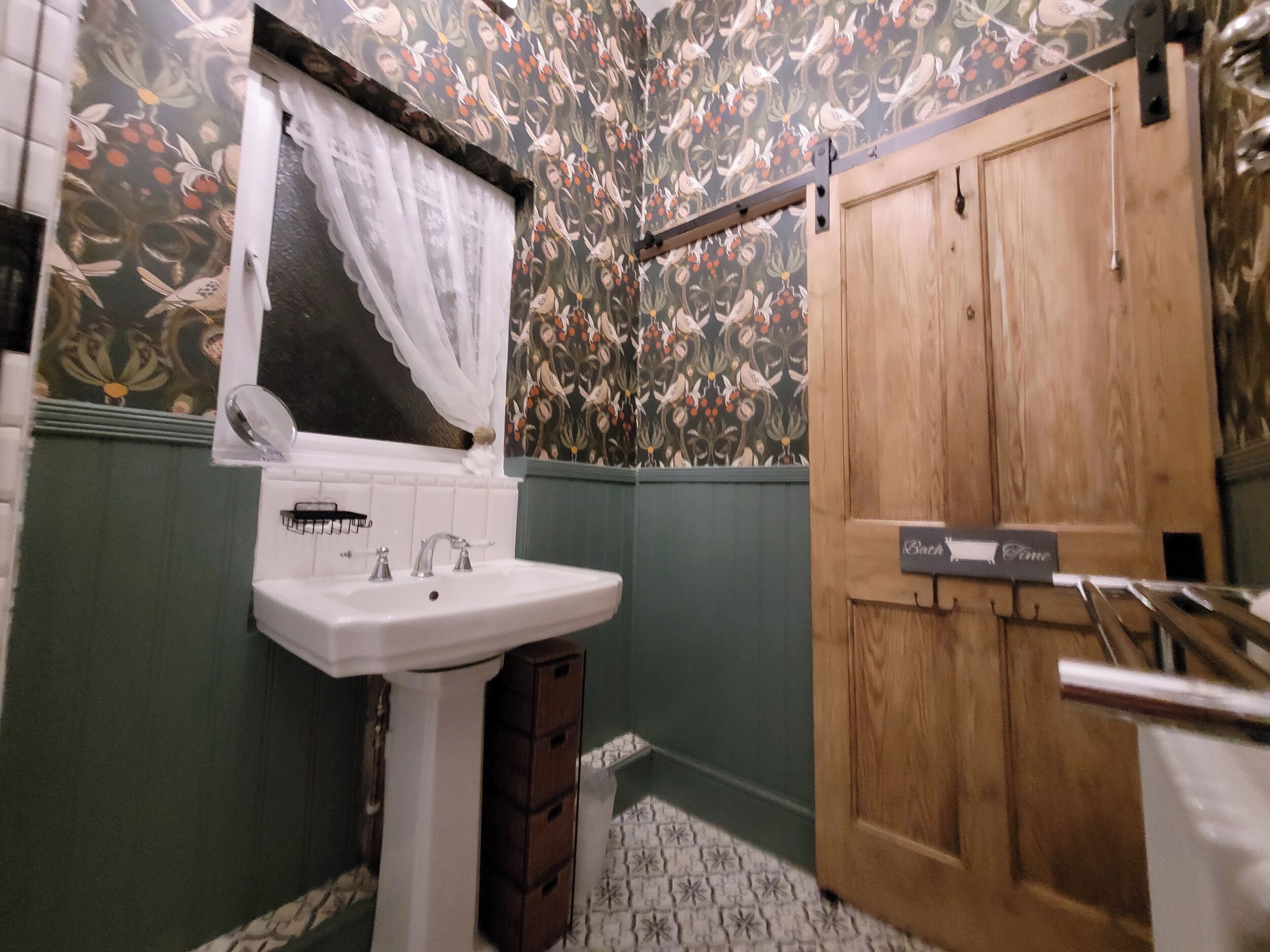 A bathroom with a white sink, green walls, and a wooden door.