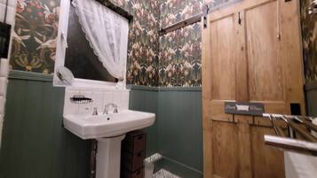 A bathroom with a white sink, green walls, and a wooden door.