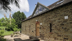 A stone building with a wooden door, a small window, and a brick wall. - The Coach House (Ludlow)