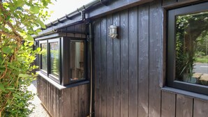 A building with dark wooden siding, large windows, and a metal gutter system. - The Haven (Scarborough)