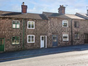 A two-story stone building with a traditional design, featuring a central door, multiple windows, and a chimney. - Bear Cottage (Matlock)