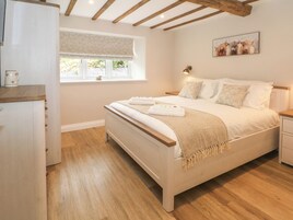Un dormitorio con cama, mesitas de noche, una ventana con vistas y un cuadro en la pared.