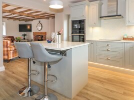 Una cocina moderna con una isla central, taburetes de bar y un horno empotrado.